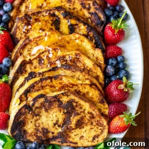 Elevated Sourdough French Toast 10 Perfectly golden slices of Sourdough French Toast arranged on a pristine white oval plate, ready to be served.