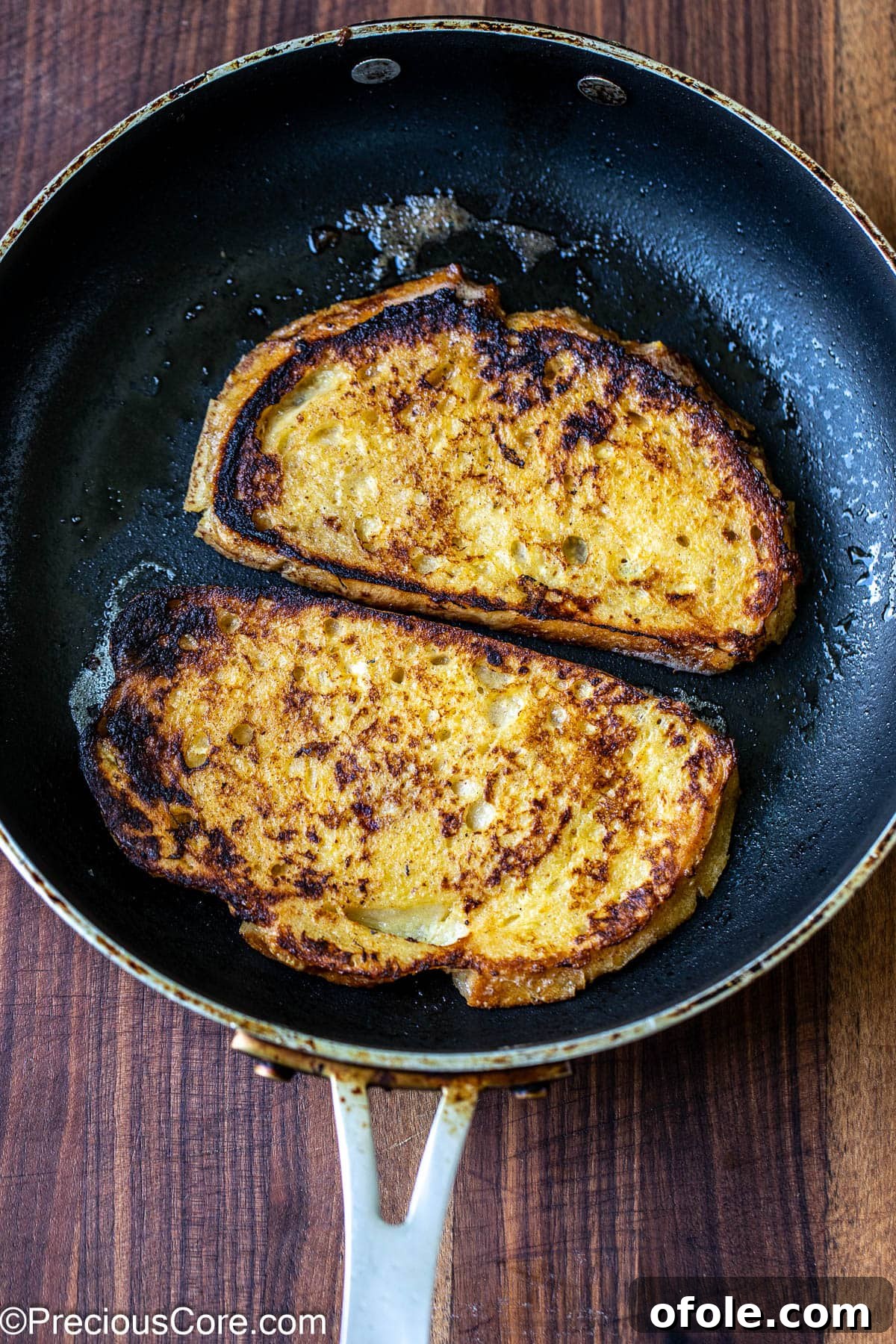 Elevated Sourdough French Toast 8 Two enticing slices of sourdough bread expertly cooking in a sizzling skillet, turning golden brown.