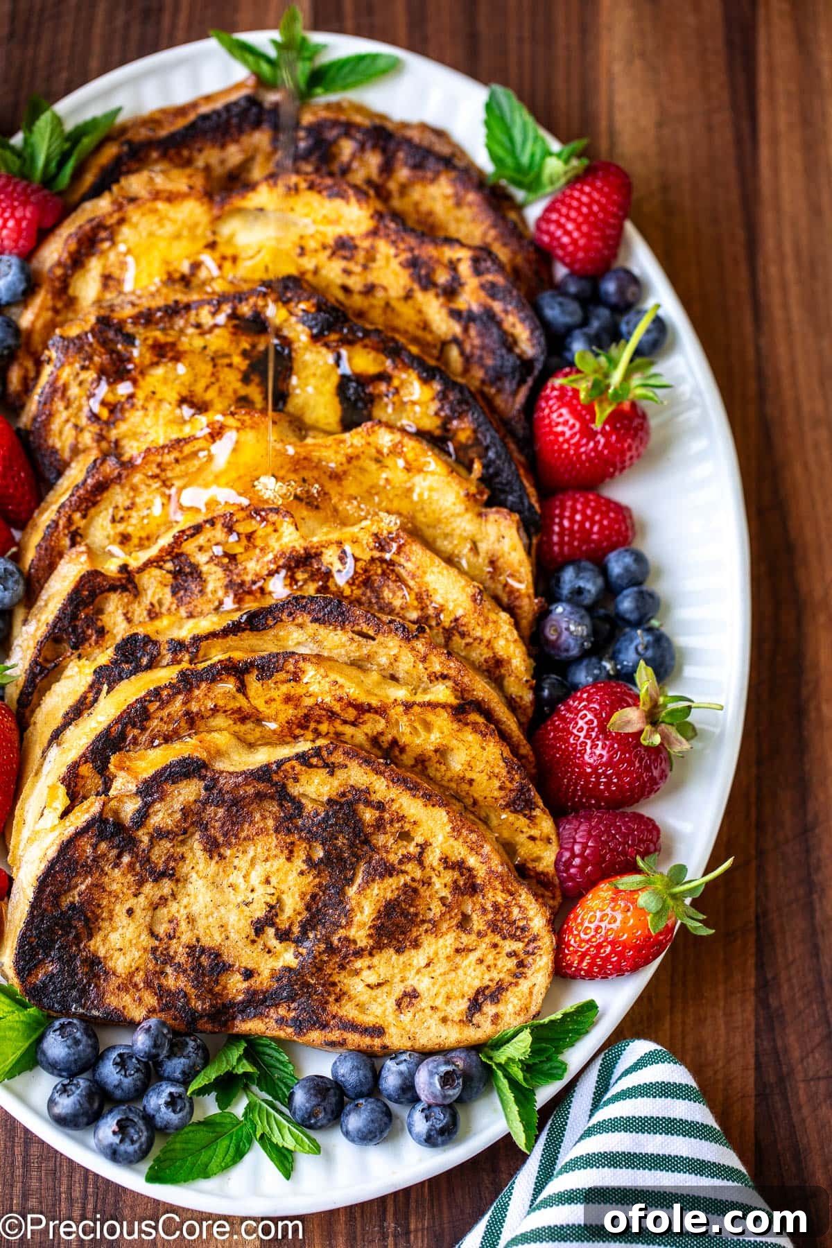 Elevated Sourdough French Toast 9 A beautifully presented plate of Sourdough French Toast, adorned with vibrant fresh berries and a rich pour of syrup.