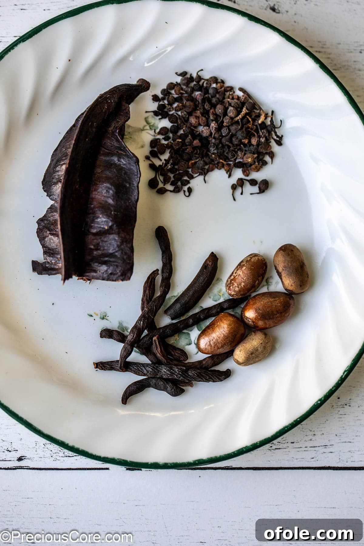 Zesty Catfish Pepperpot 5 Aidan fruit, African black pepper, negro pepper, and African nutmeg on a white plate.