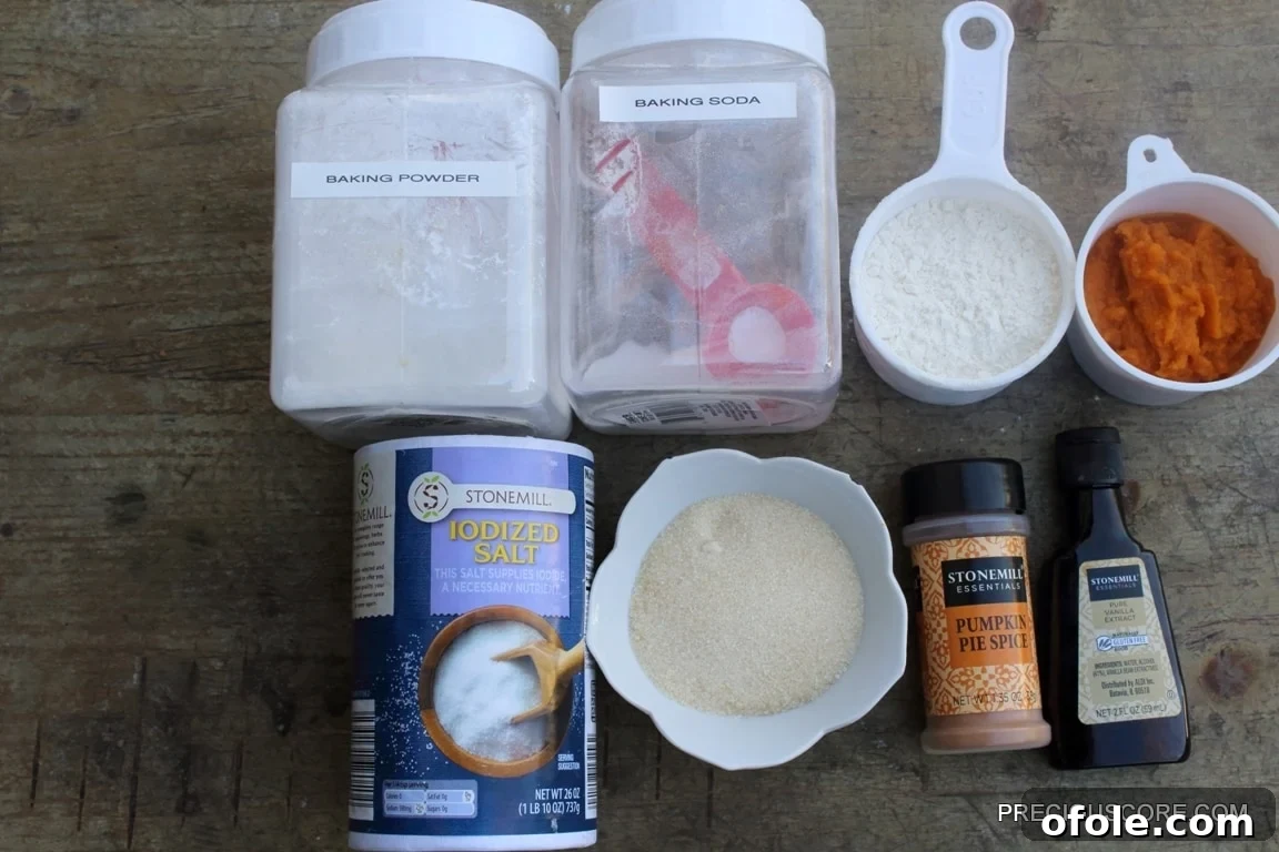 Spiced Pumpkin Swirl Cake 4 Essential dry ingredients for baking pumpkin roll cake, including all-purpose flour, baking powder, salt, and a container of pumpkin pie spice, neatly arranged.