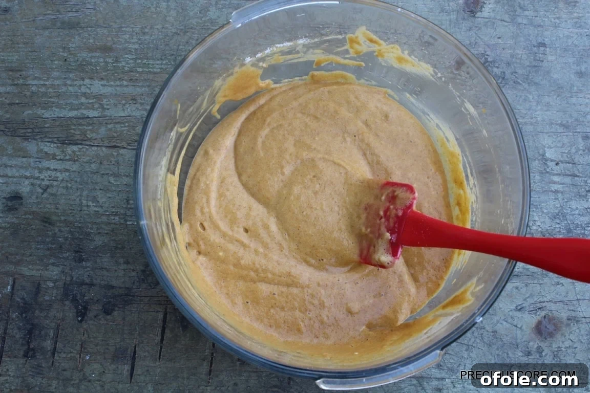 Spiced Pumpkin Swirl Cake 10 A vibrant bowl of pumpkin roll cake batter, perfectly mixed and ready to be spread into the baking pan.