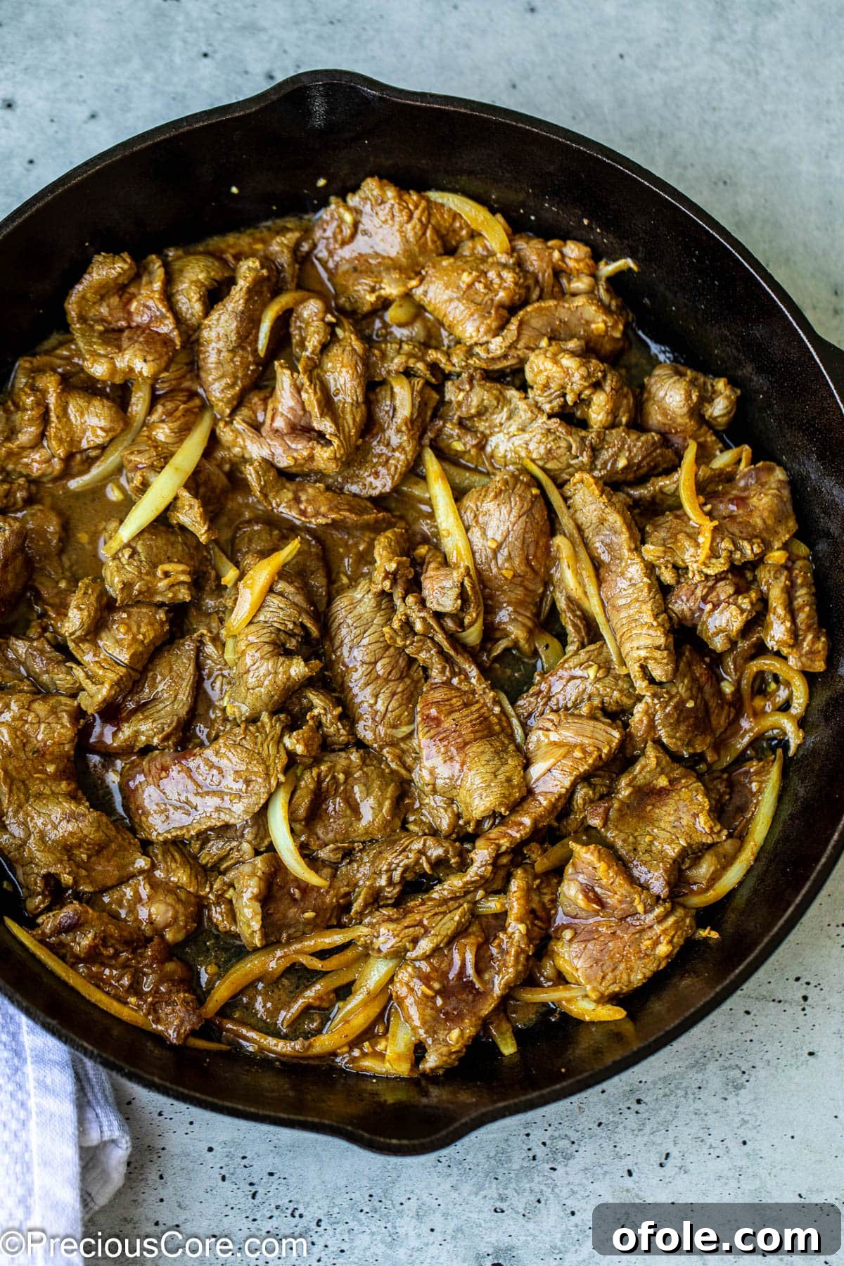 Marinated beef shawarma strips sizzling and cooking in a hot skillet on the stovetop.