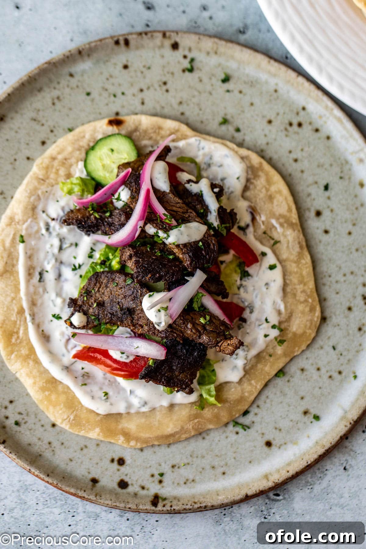 A delicious flatbread wrap filled with tender beef shawarma, fresh vegetables, and a creamy sauce.