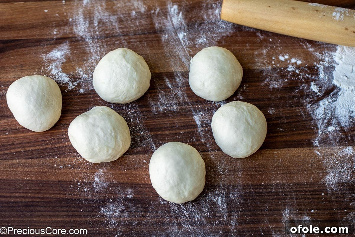 Shawarma Flatbread Delights 8 Six evenly divided pieces of dough, expertly shaped into smooth balls on a floured surface.