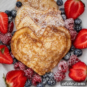 Heart shaped pancakes on a plate with berries, beautifully presented.