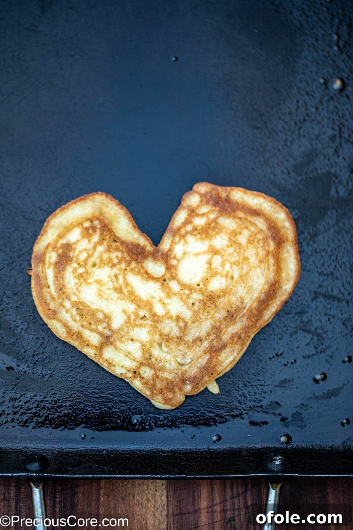 Sweetheart Flapjacks 7 A beautifully cooked golden-brown heart-shaped pancake resting on a griddle, indicating it's ready to be served.