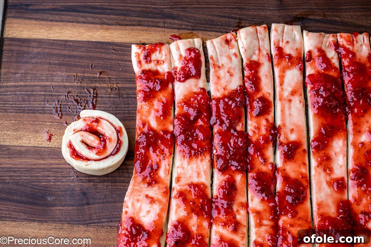 Luscious Strawberry Cinnamon Rolls 15 The process of rolling a strawberry cinnamon bun from a strip of dough.