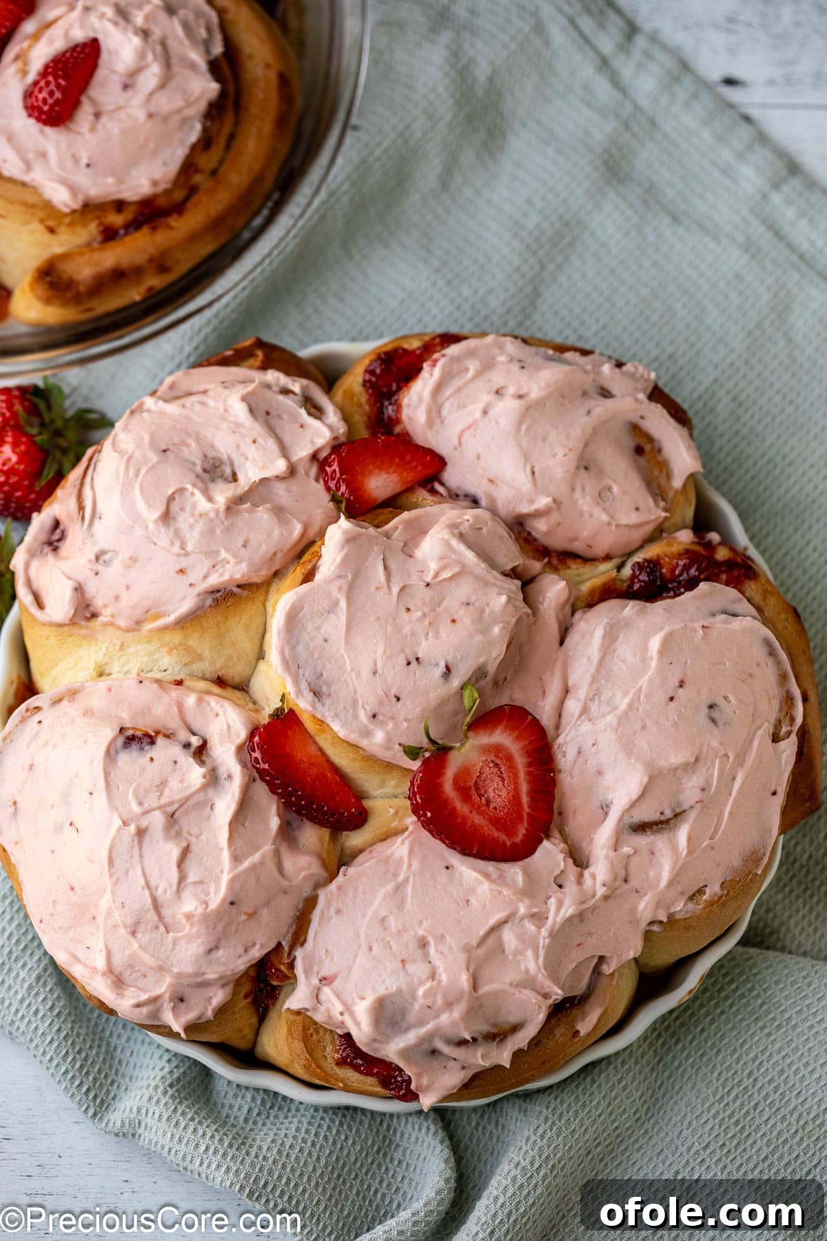 Luscious Strawberry Cinnamon Rolls 19 Frosted strawberry cinnamon rolls in a round baking dish, ready to be served.