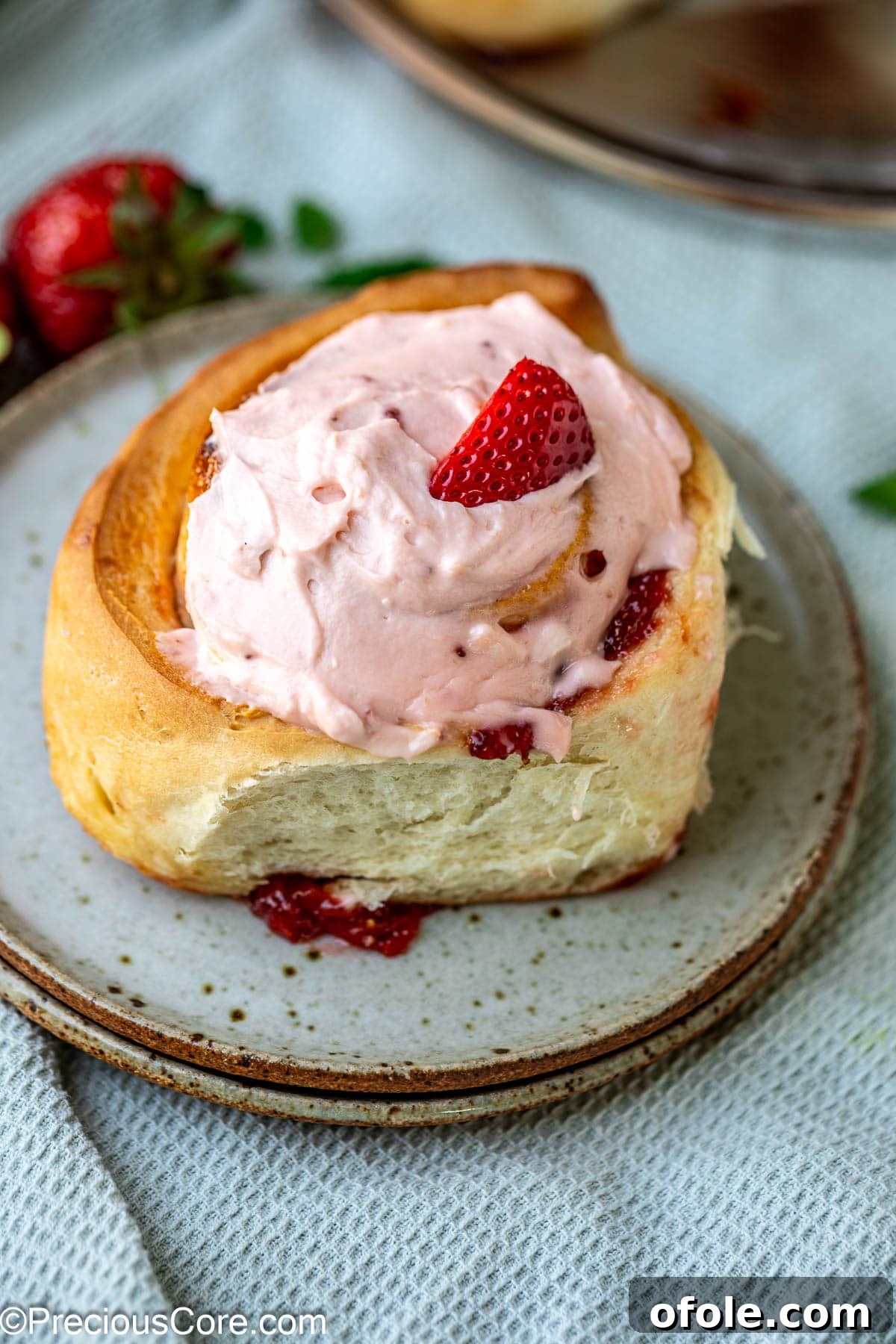 Luscious Strawberry Cinnamon Rolls 3 A single strawberry cinnamon roll garnished with a fresh strawberry slice.