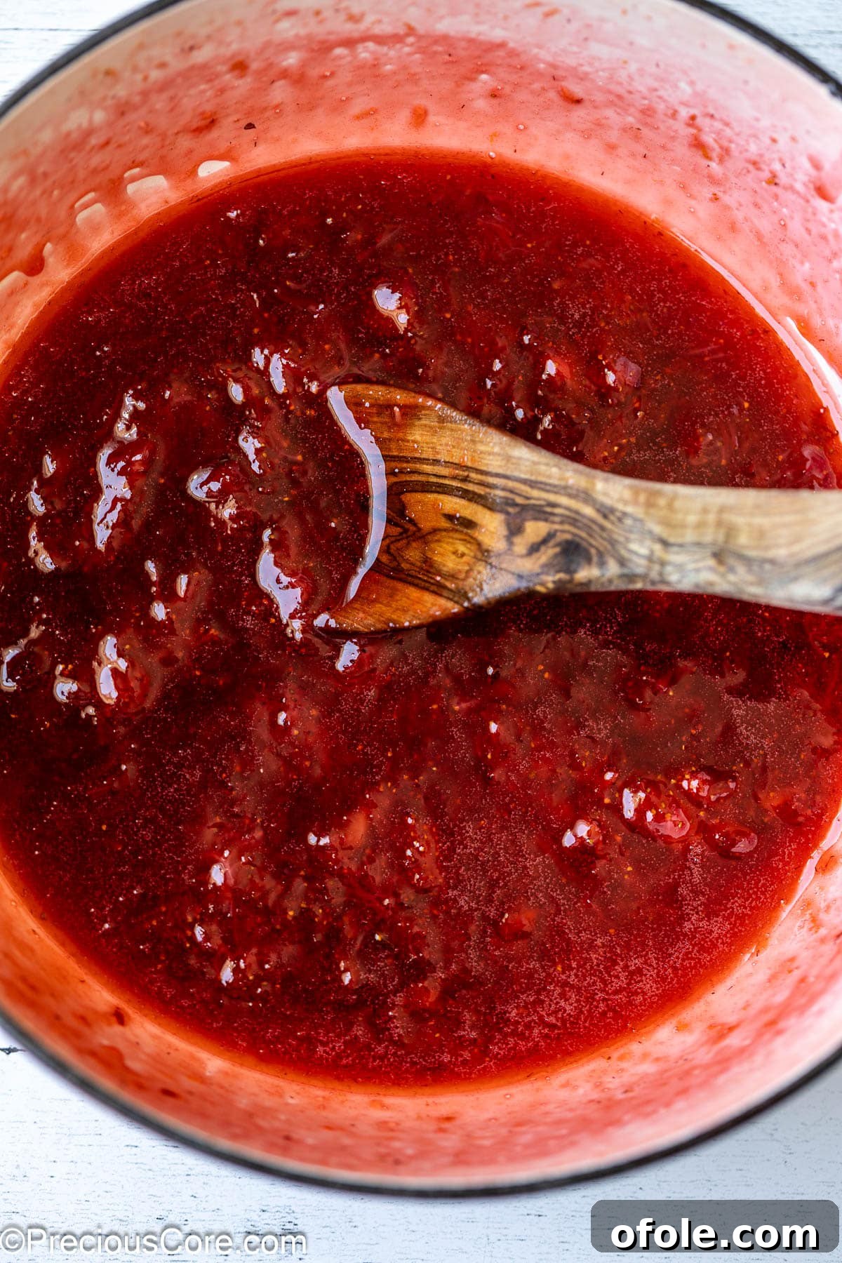 Luscious Strawberry Cinnamon Rolls 8 Mixing strawberry compote with a wooden spoon in a saucepan.