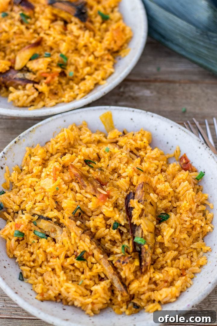Palm oil jollof rice served in several small bowls, garnished with fresh greens.