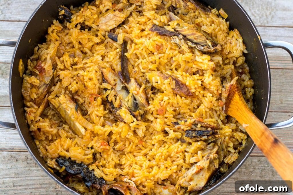 Fluffed palm oil jollof rice in a pot, with distinct grains and rich color, ready to be served.