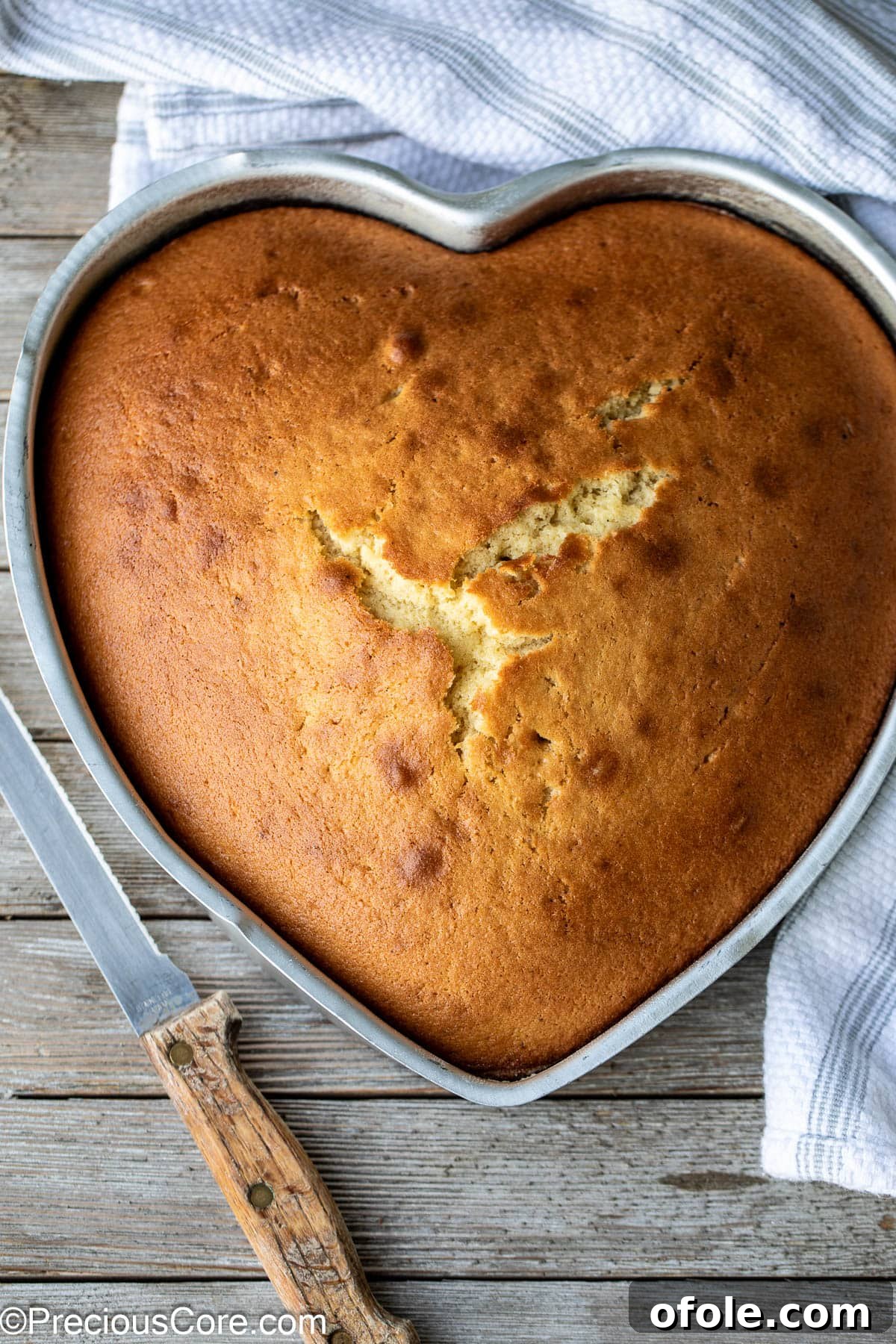 Effortless Everyday Cake 2 A beautifully baked plain cake in a heart-shaped pan, with a silver serving knife resting beside it, highlighting its tender texture.