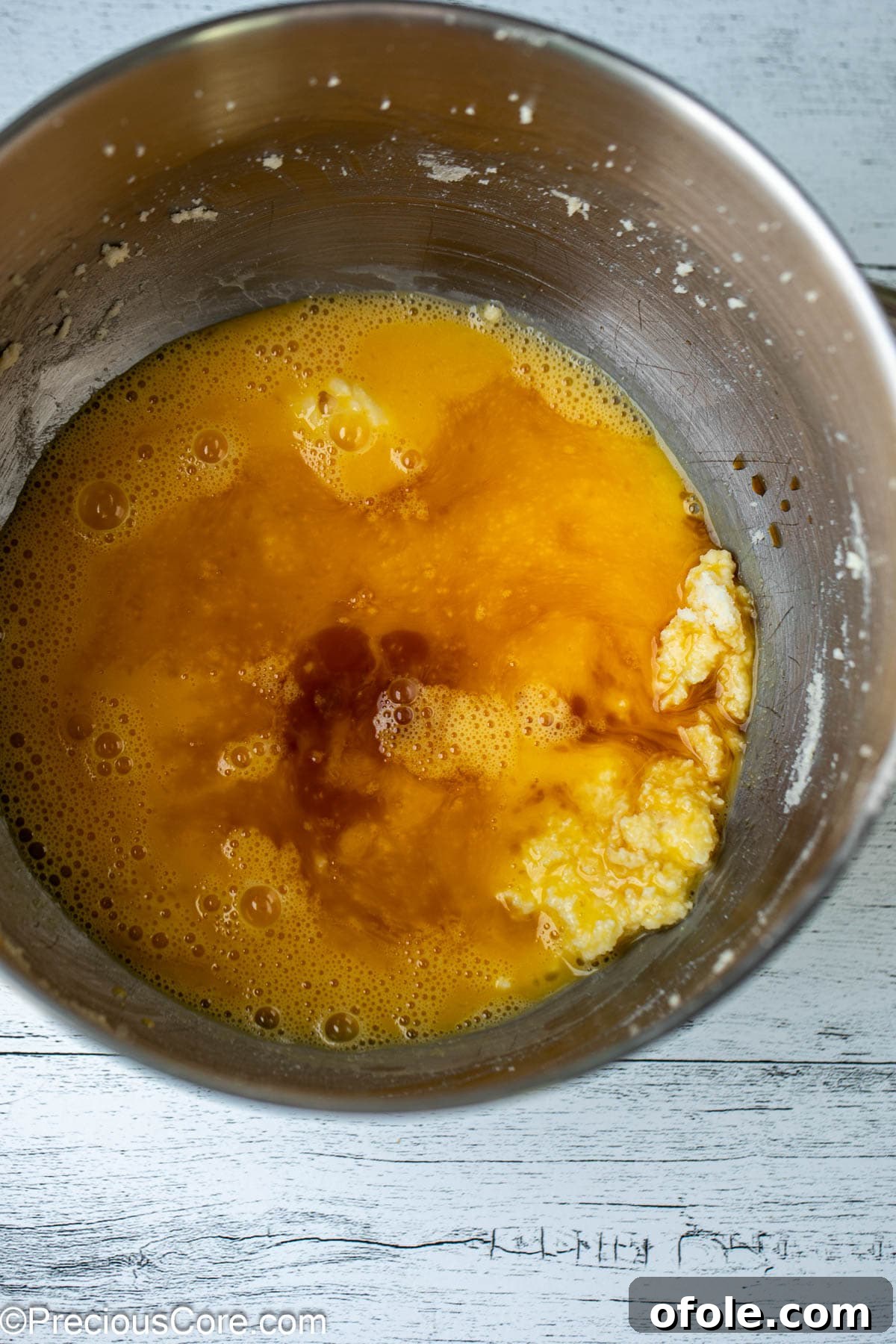 Effortless Everyday Cake 6 A mixing bowl containing the wet ingredients for the cake batter: eggs, vanilla extract, and the creamed butter and sugar.