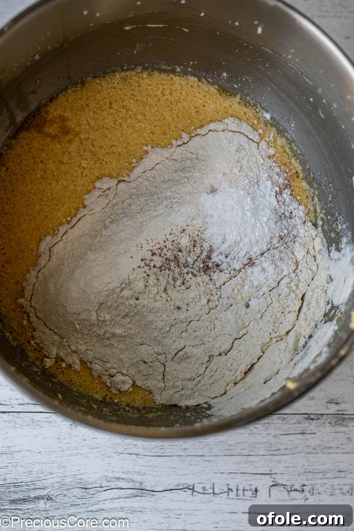 Effortless Everyday Cake 7 Dry ingredients, including flour, baking powder, and nutmeg, being gently mixed into the cake batter.