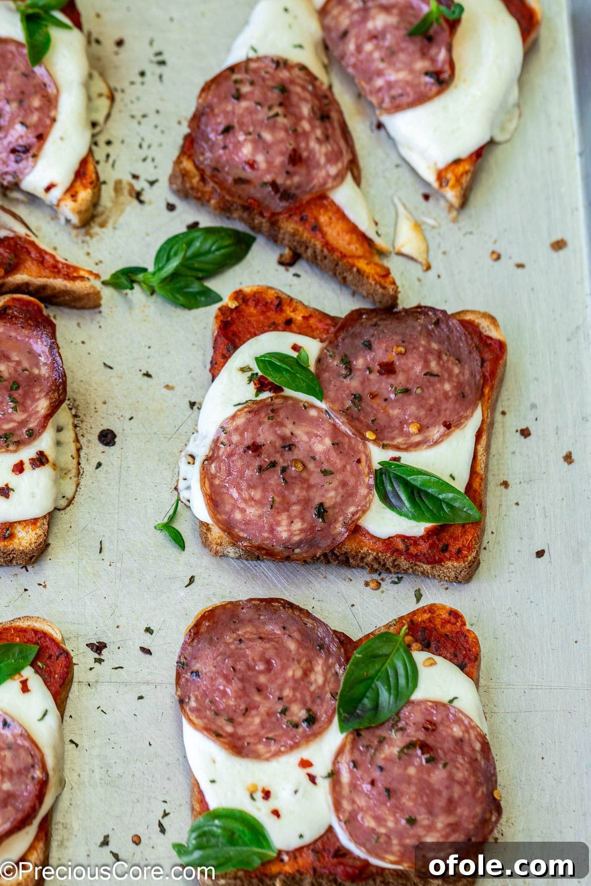Close-up of pizza toasts on baking sheet.
