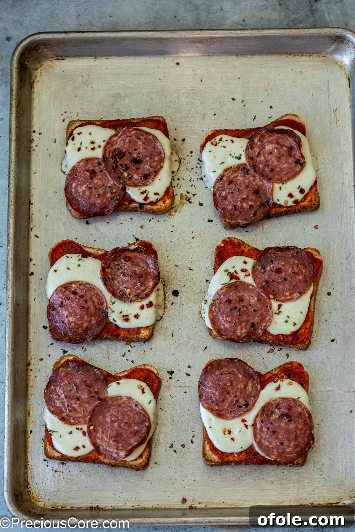 Baked pizza toasts on baking sheet.