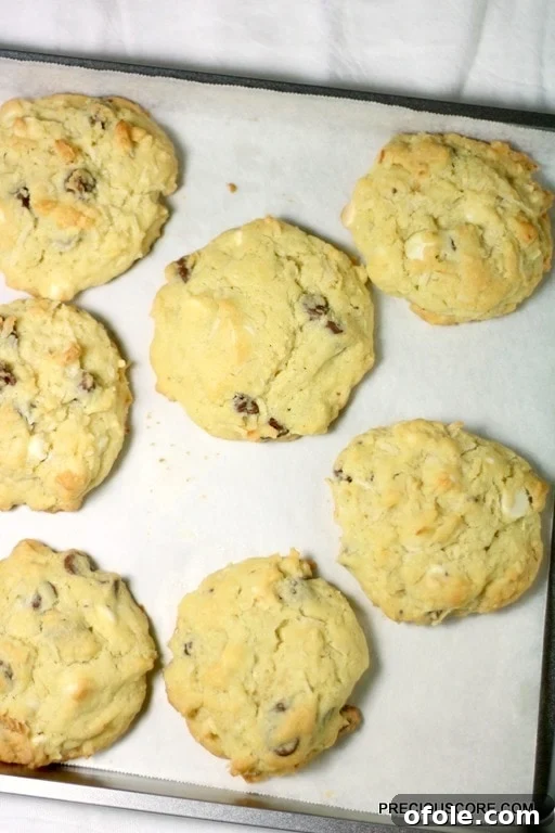 Tropical Coconut Chocolate Chip Cookies 6 Coconut chocolate chip cookies on a lined baking sheet.