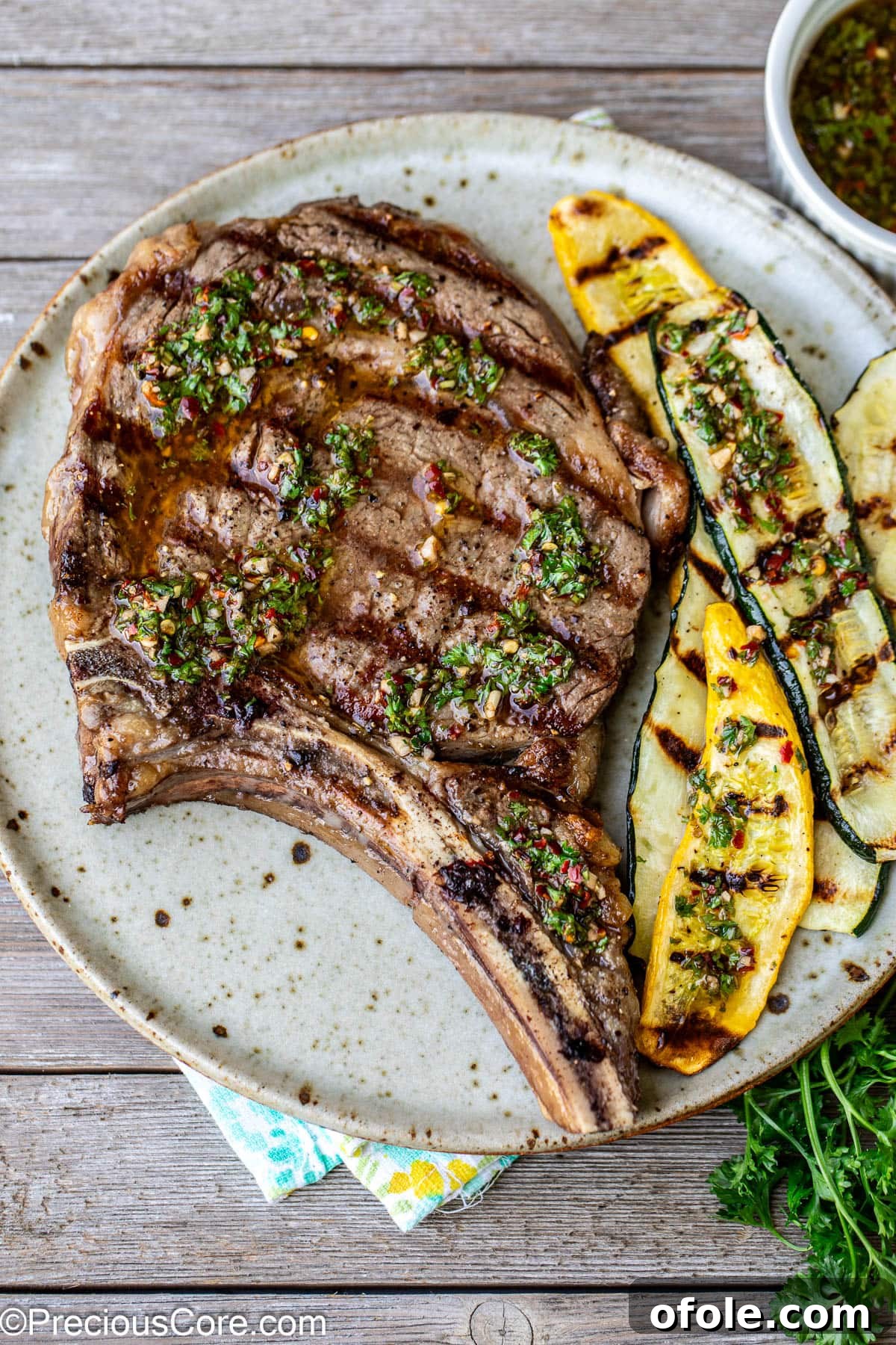 Prime Bone-In Ribeye 2 Bone-In Ribeye steak on a plate served with grilled zucchini.