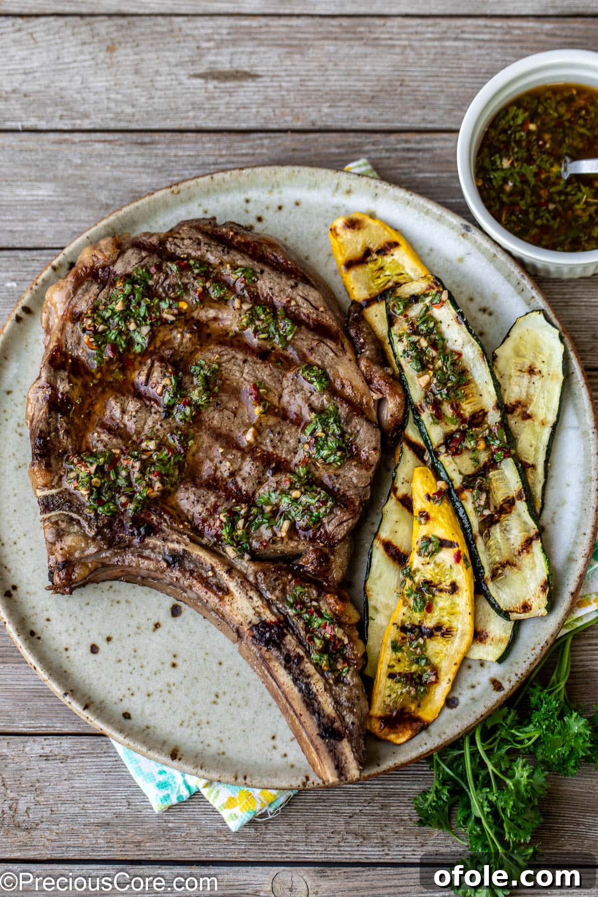 Prime Bone-In Ribeye 3 Overhead shot of steak topped with chimichurri and served with zucchini.