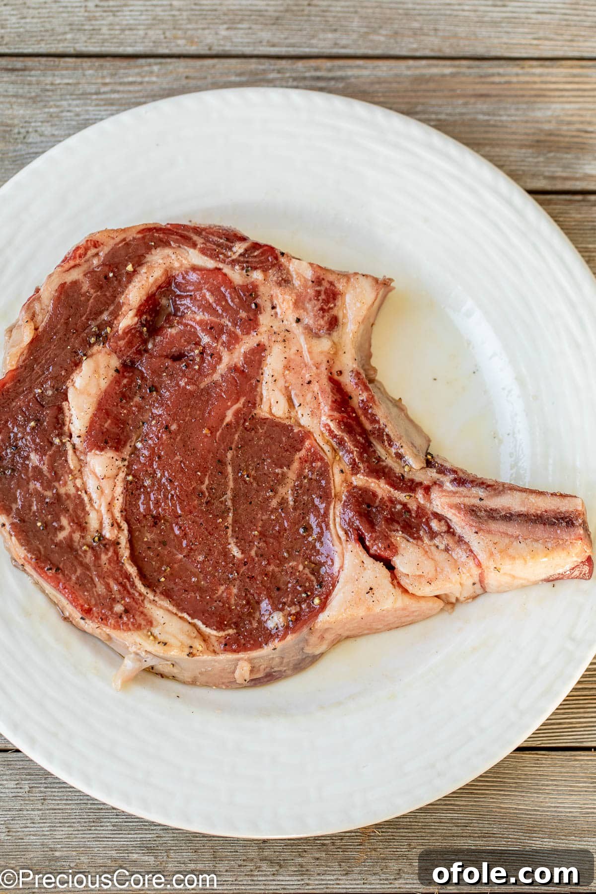 Prime Bone-In Ribeye 5 Bone-in steak seasoned with salt and pepper.
