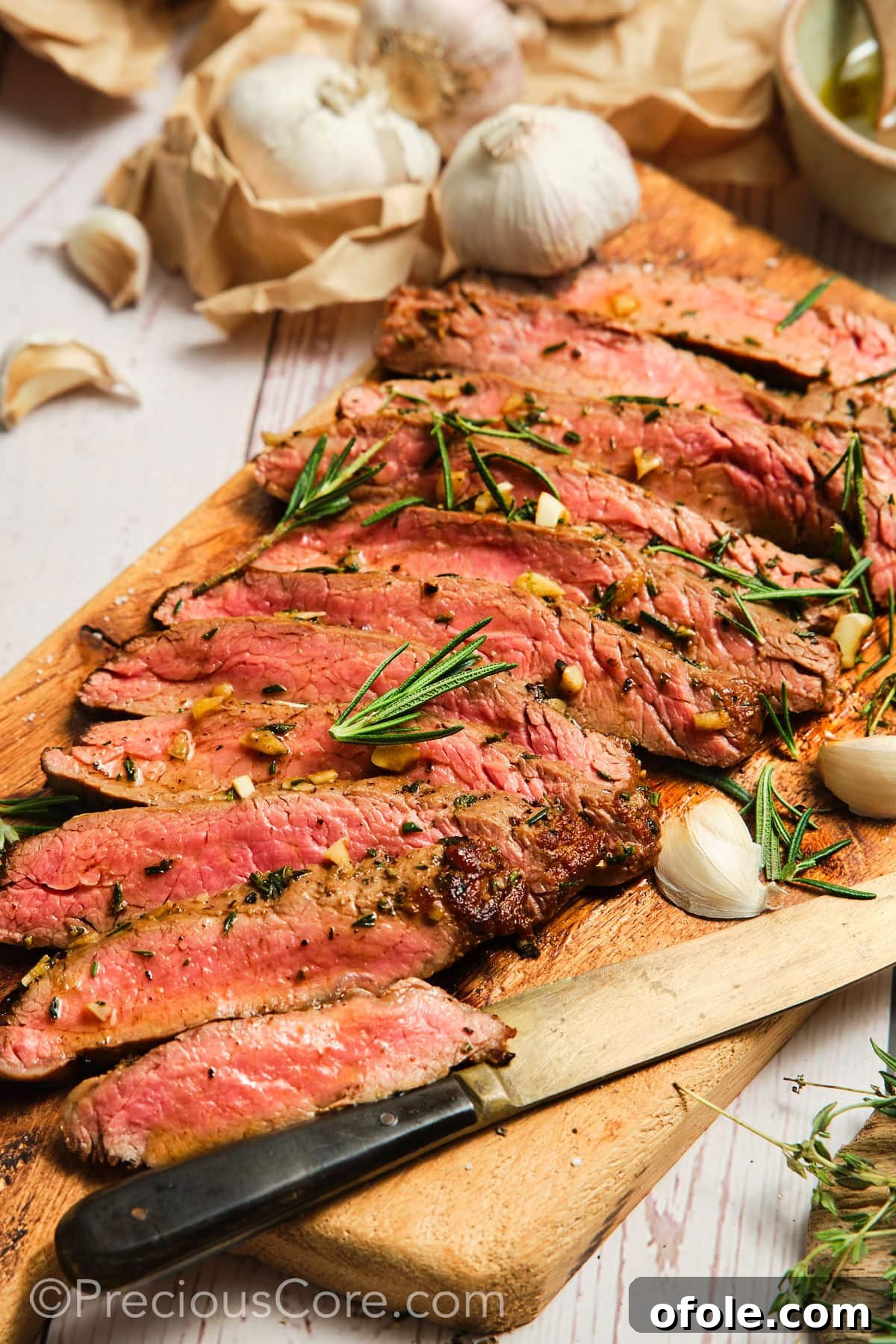 Sliced pan seared flank steak on a cutting board, showcasing a perfect medium-rare center.