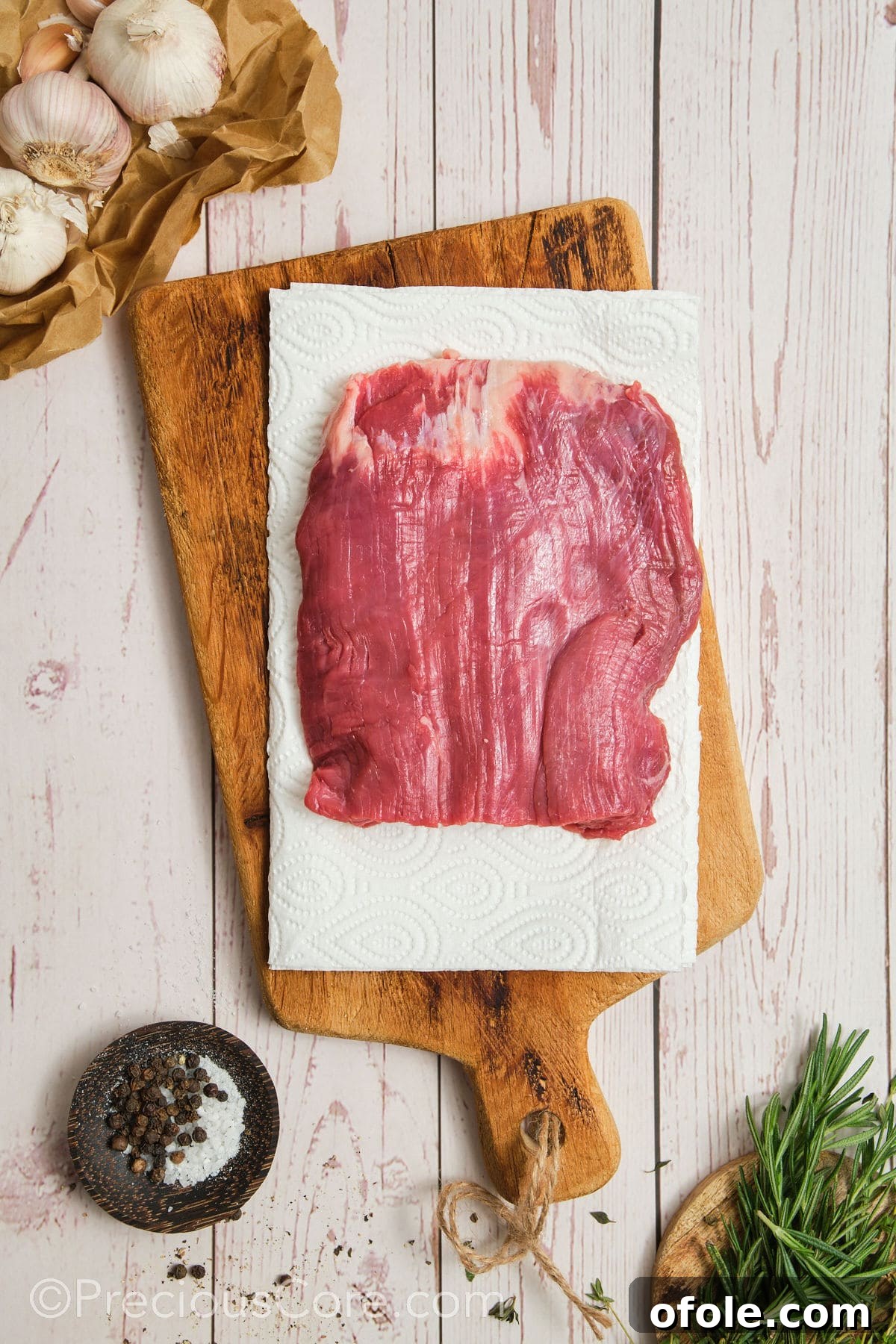 Patting dry flank steak with paper towels to remove moisture for a better sear.