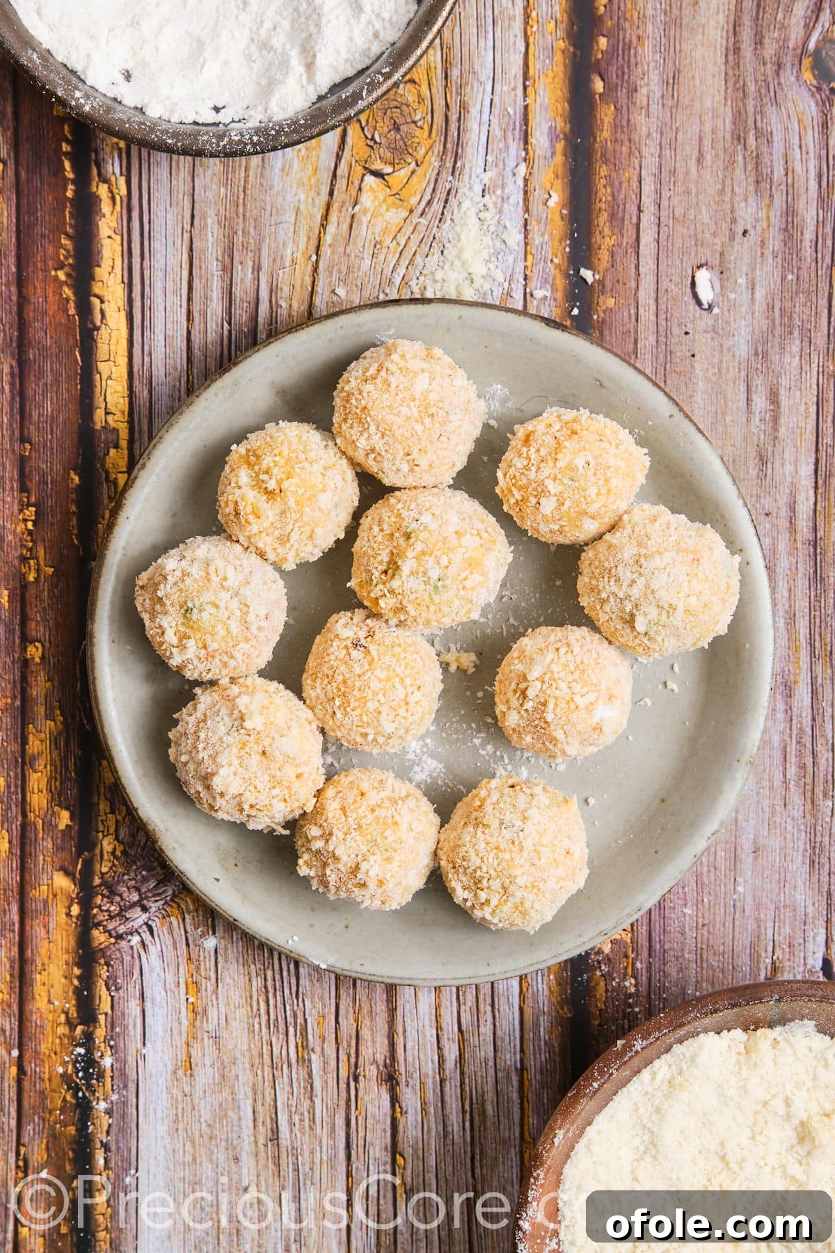 A tray of fully coated potato cheese balls, ready for frying.
