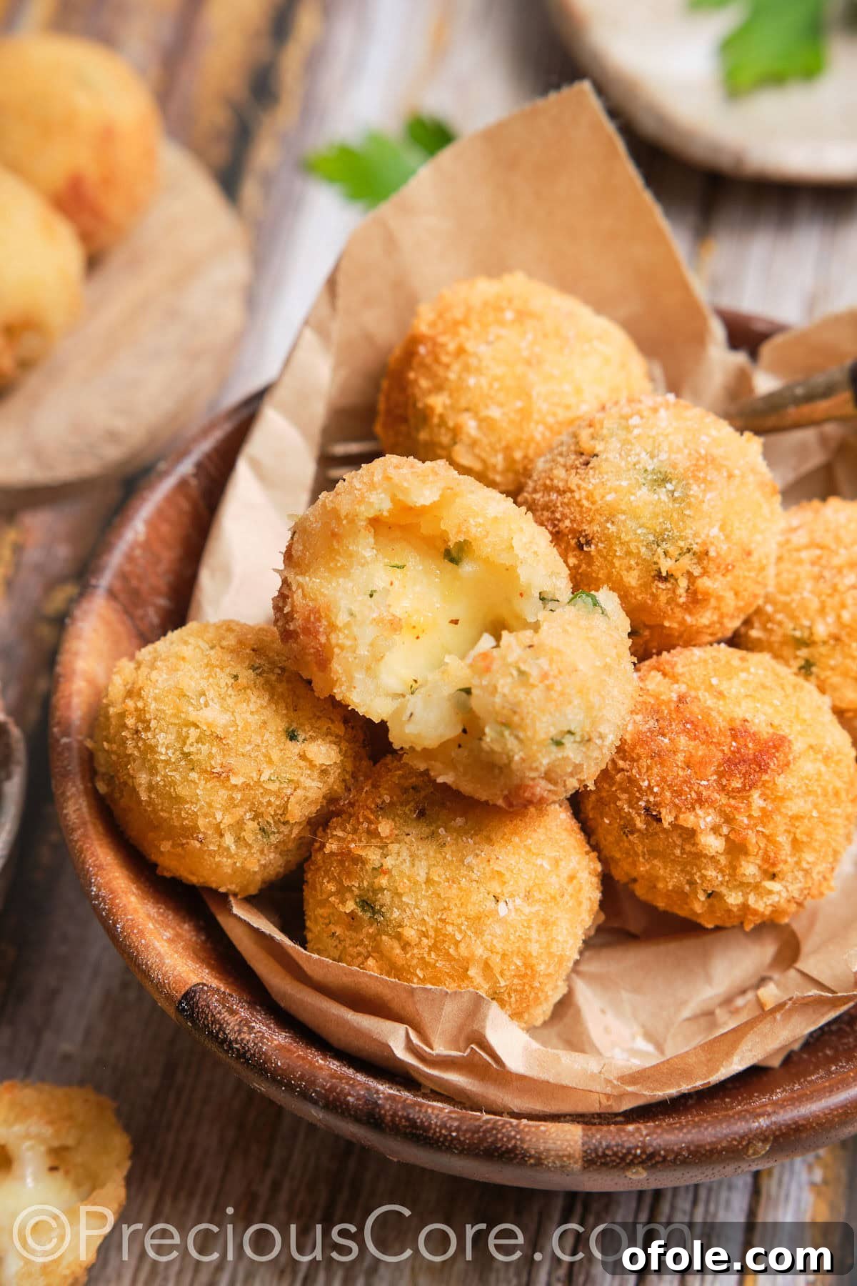 The perfect homemade potato cheese balls, golden and inviting, with one partially broken to reveal melted cheese.