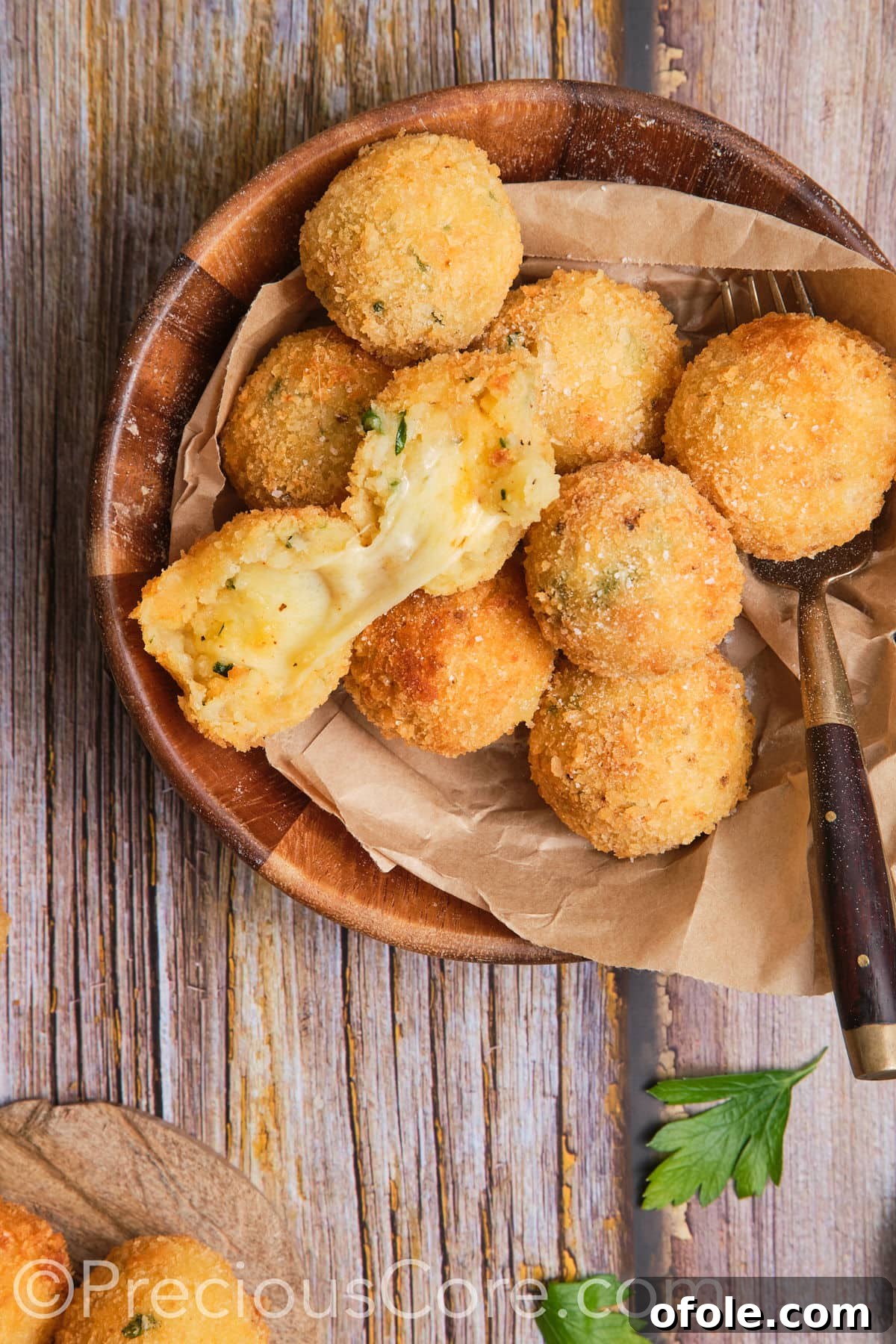 Golden brown cheese potato balls in a rustic wooden bowl, ready to be enjoyed.