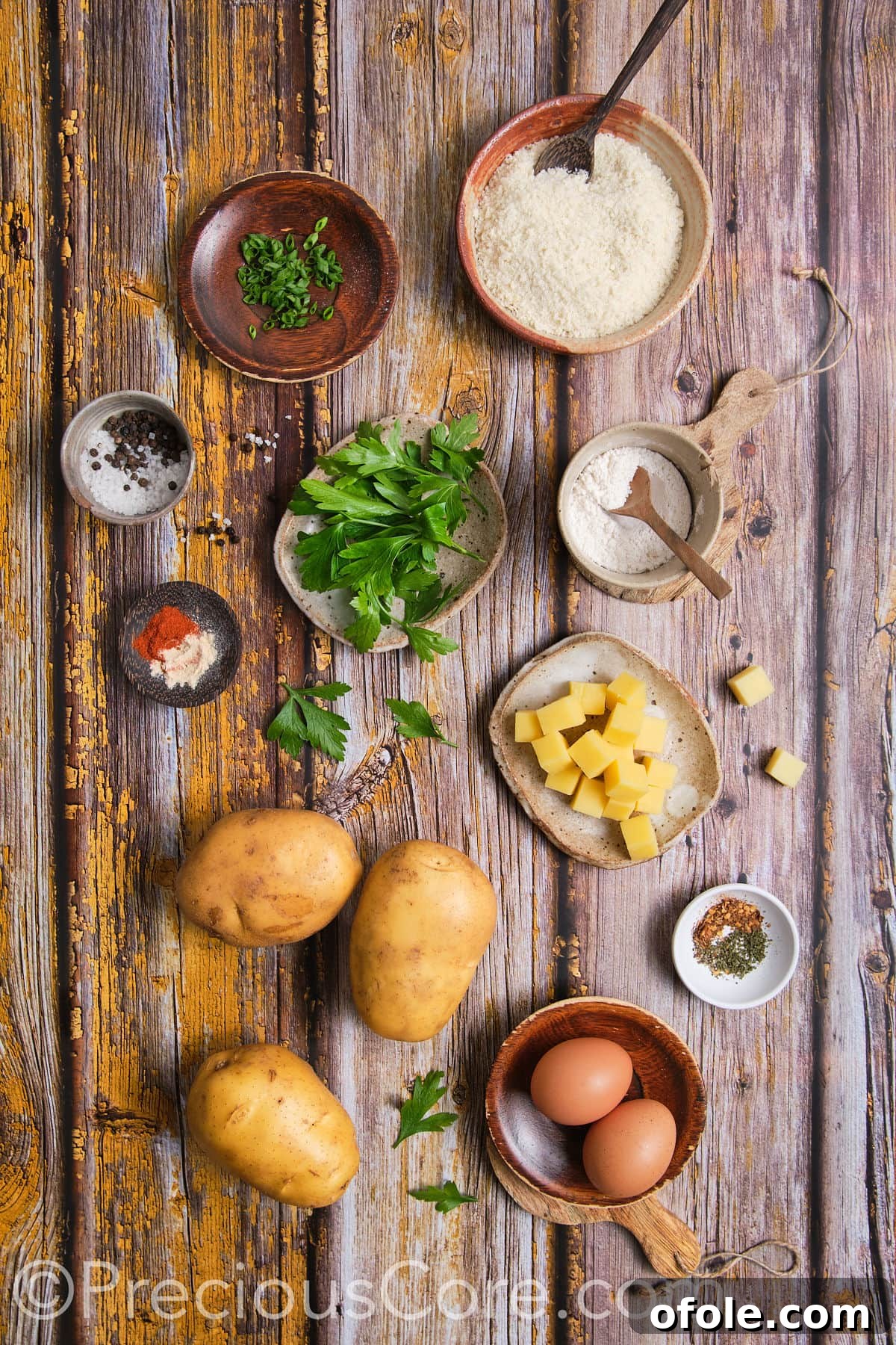 All the fresh ingredients laid out for making potato cheese balls: potatoes, cheese, herbs, and spices.