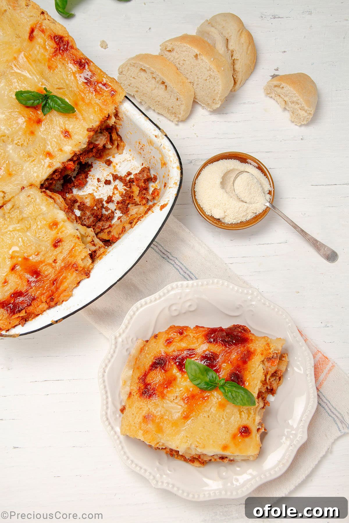 Creamy Béchamel Lasagna 2 A perfectly baked slice of Lasagna with Béchamel Sauce resting on a white plate, with a large baking dish filled with the freshly prepared lasagna in the background, steam gently rising.