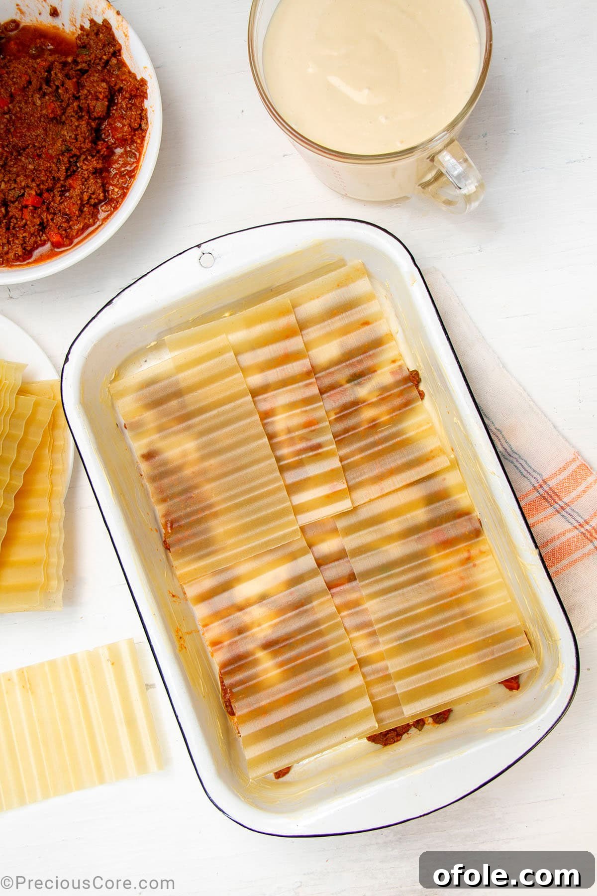 Creamy Béchamel Lasagna 13 Dry, no-boil lasagna noodles neatly layered over a base of meat sauce in a rectangular baking dish, ready for subsequent layers.