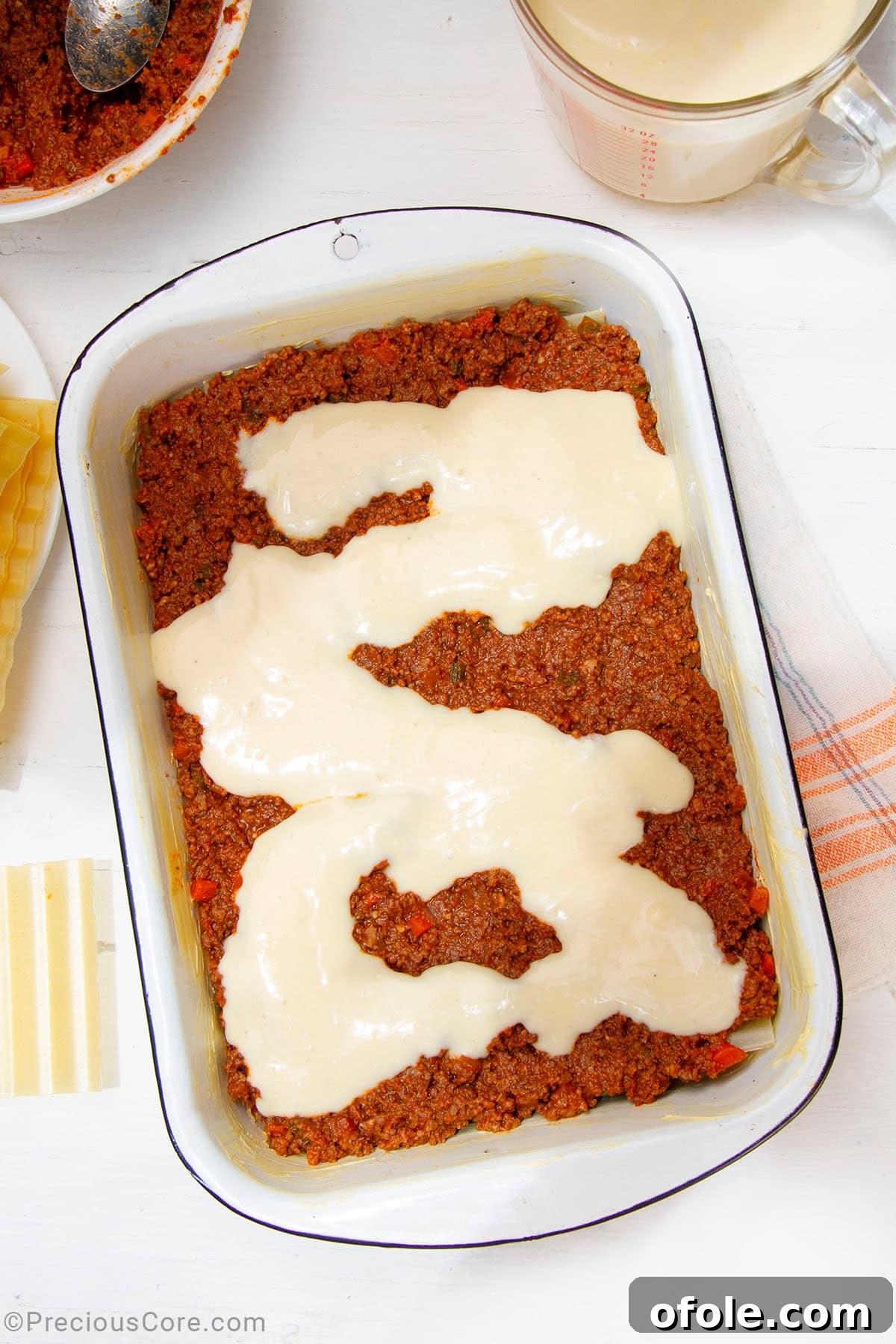 Creamy Béchamel Lasagna 14 A rich layer of homemade béchamel sauce spread over the Bolognese and pasta layers in a baking dish, showcasing the creamy filling of the lasagna.