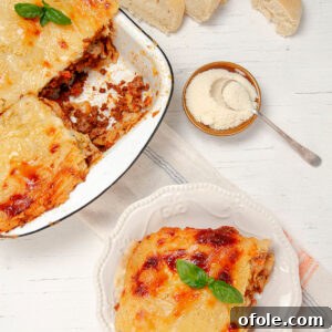 Creamy Béchamel Lasagna 16 A beautifully presented slice of Lasagna with Béchamel Sauce on a plate, alongside a baking dish of the full lasagna.