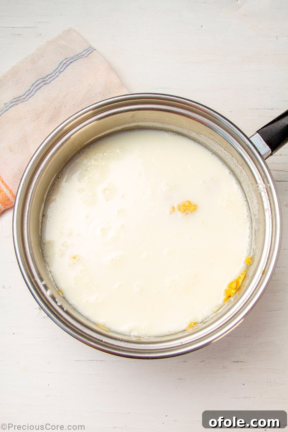 Creamy Béchamel Lasagna 9 Warm milk being gradually added to a golden roux in a saucepan, with a whisk actively stirring the mixture to create a smooth béchamel sauce.