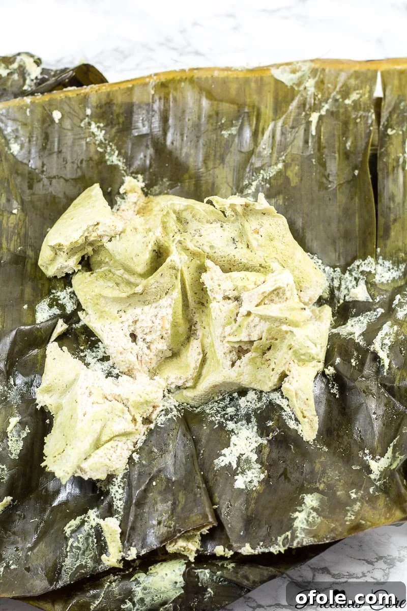 Bundles of egusi pudding wrapped in banana leaves and tied, neatly arranged in a pot for steaming