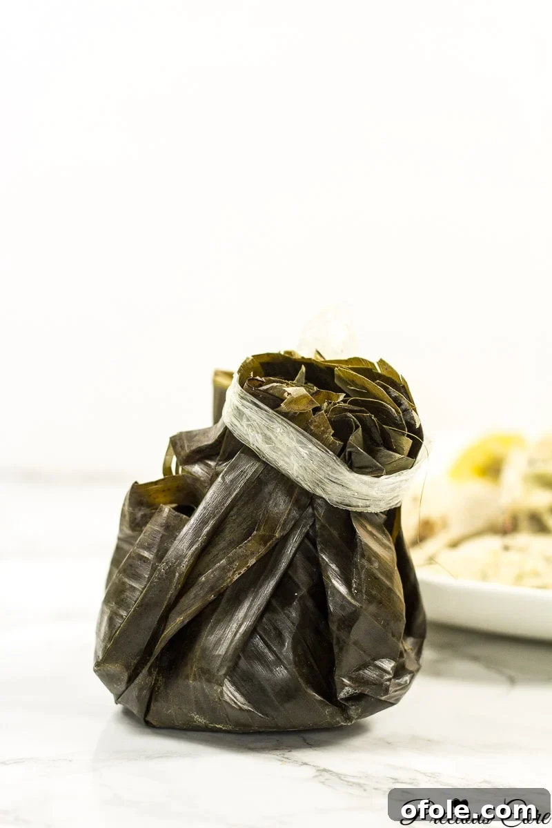 Freshly prepared Egusi Pudding mixture being carefully wrapped in plantain leaves for steaming, highlighting the traditional preparation method