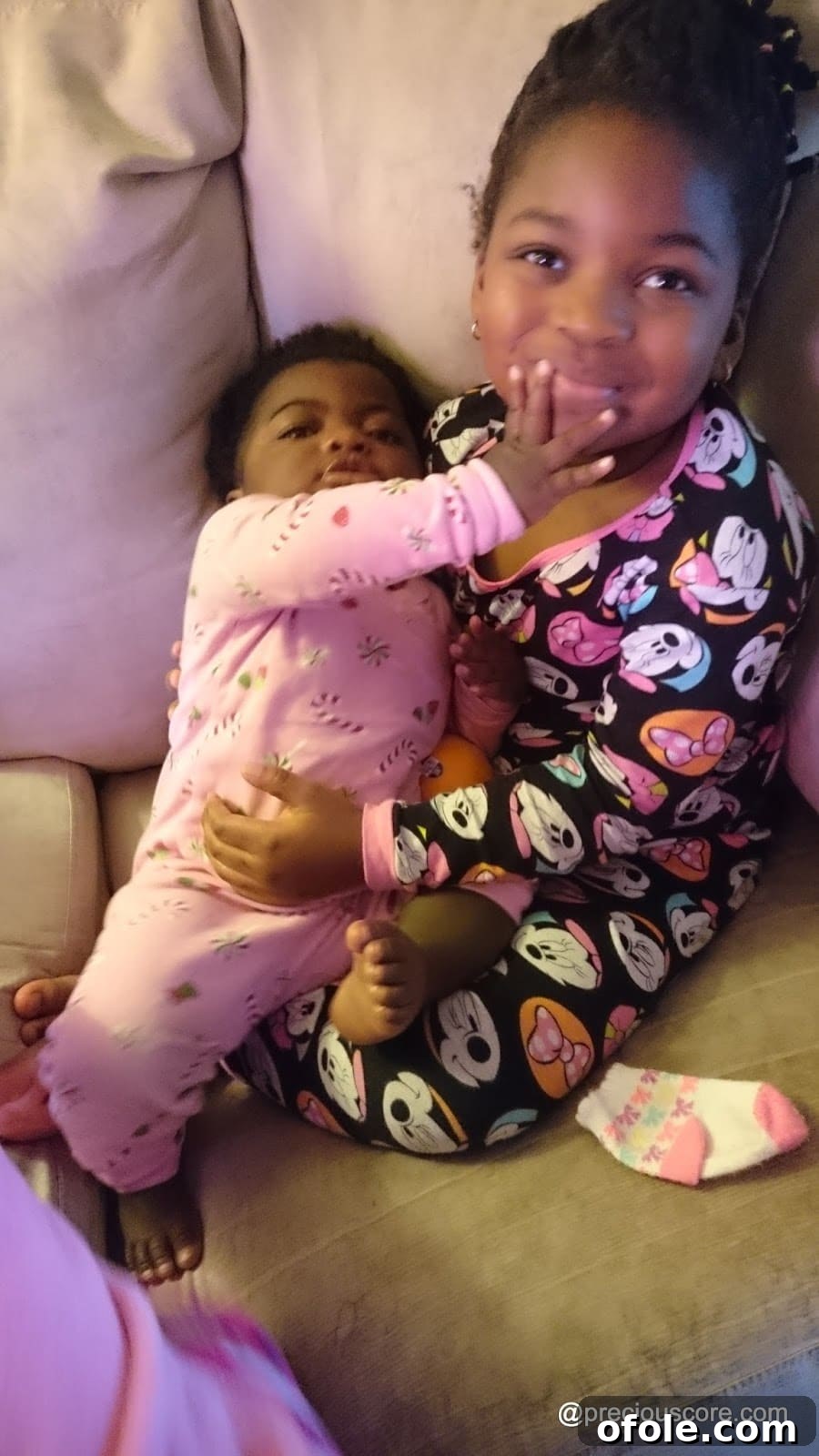 Two children lovingly cuddled together in their pyjamas
