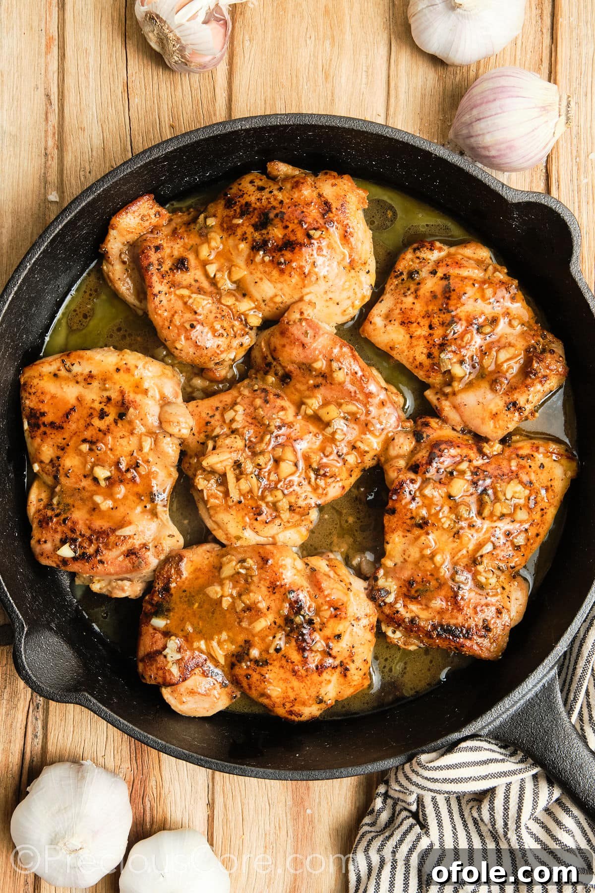 Juicy Skillet Chicken Thighs 15 Cooked chicken thighs in a cast iron skillet, being basted with melted garlic butter.