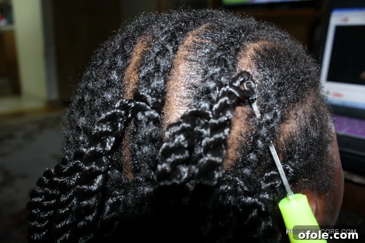 Demonstration of pulling the looped crochet hair through the cornrow foundation using the latch hook