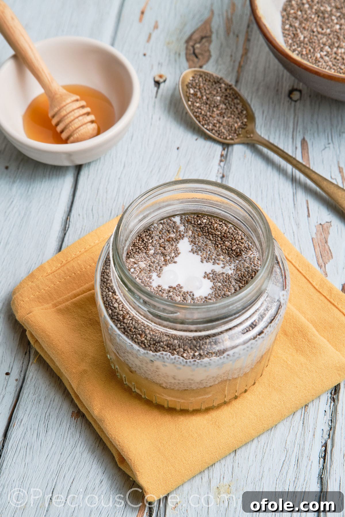 The banana chia pudding mixture being stirred in a glass jar.