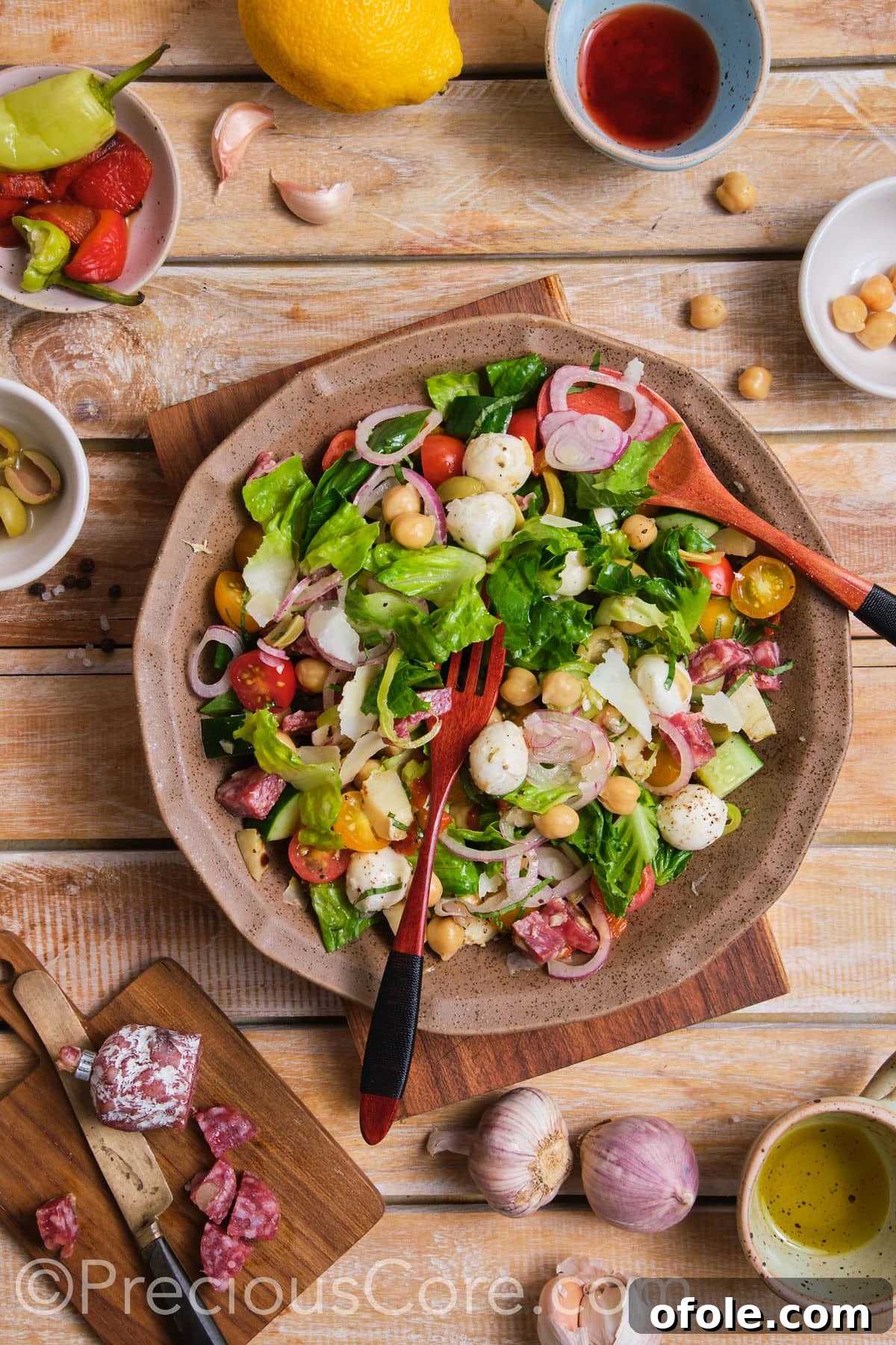 Ultimate Italian Chopped Salad 4 Hands gently tossing a vibrant Italian Chopped Salad in a large mixing bowl.