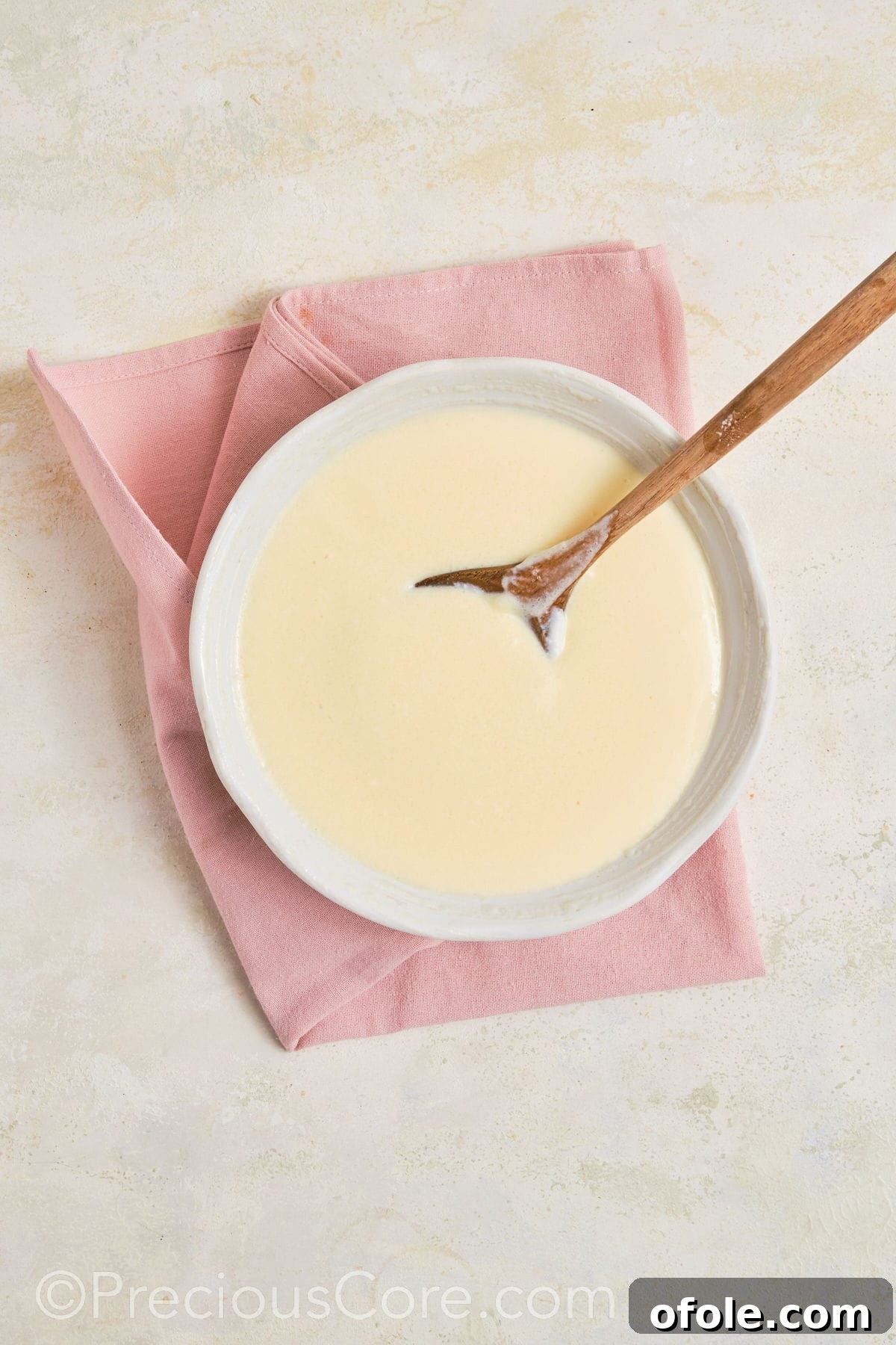 Dreamy Strawberry Banana Pudding 8 Close-up of a whisk blending vanilla pudding mix with liquid ingredients in a bowl, creating a smooth base.