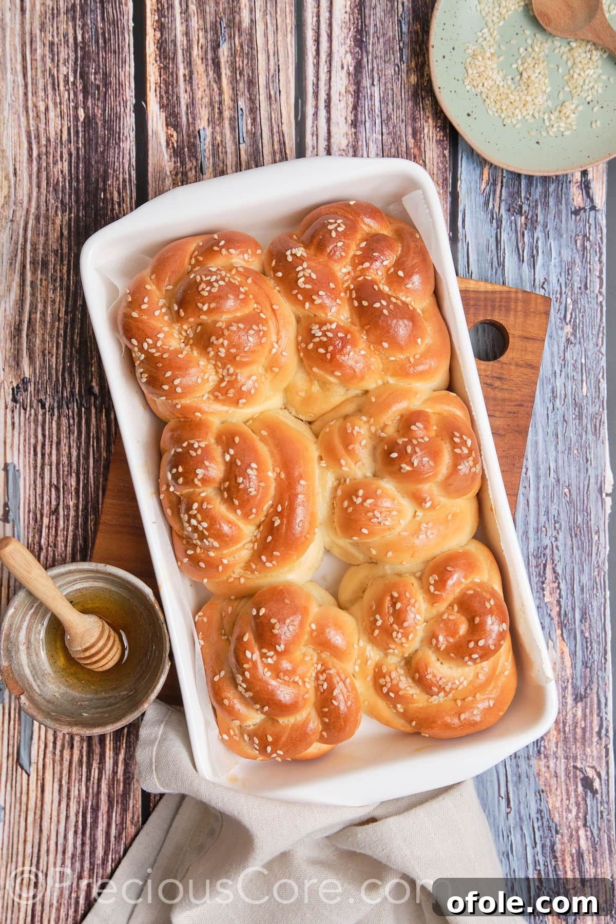 Golden brown baked challah rolls cooling on a baking sheet.