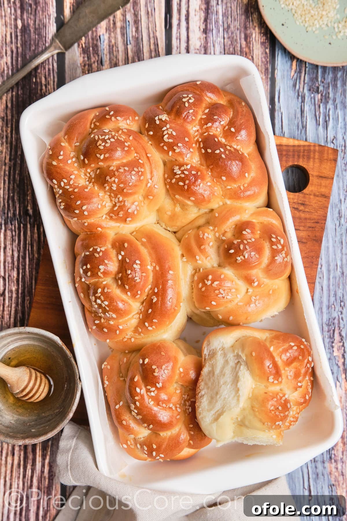 One challah roll pulled away from the main dish to showcase its perfect texture and golden crust.