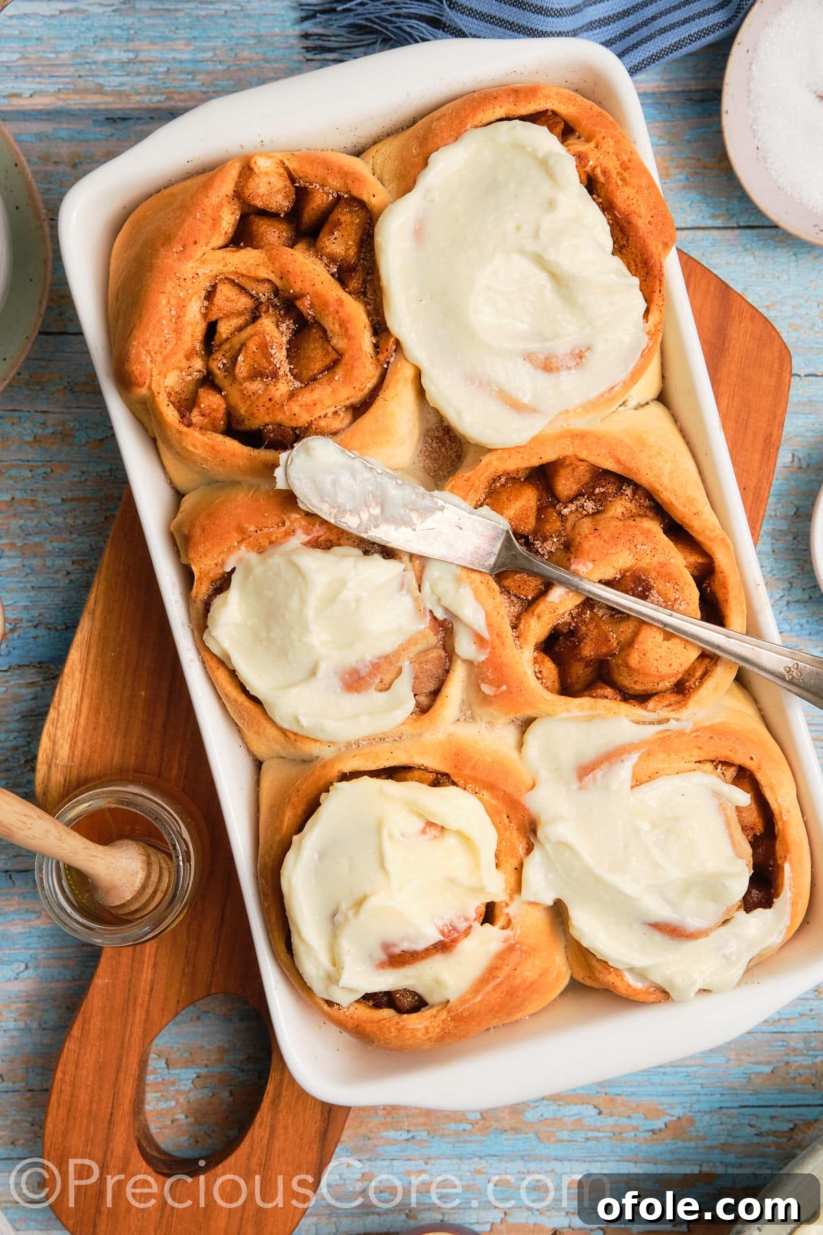 Close-up of freshly baked Cinnamon Rolls with Apple Pie Filling topped with cream cheese frosting, ready to be served.