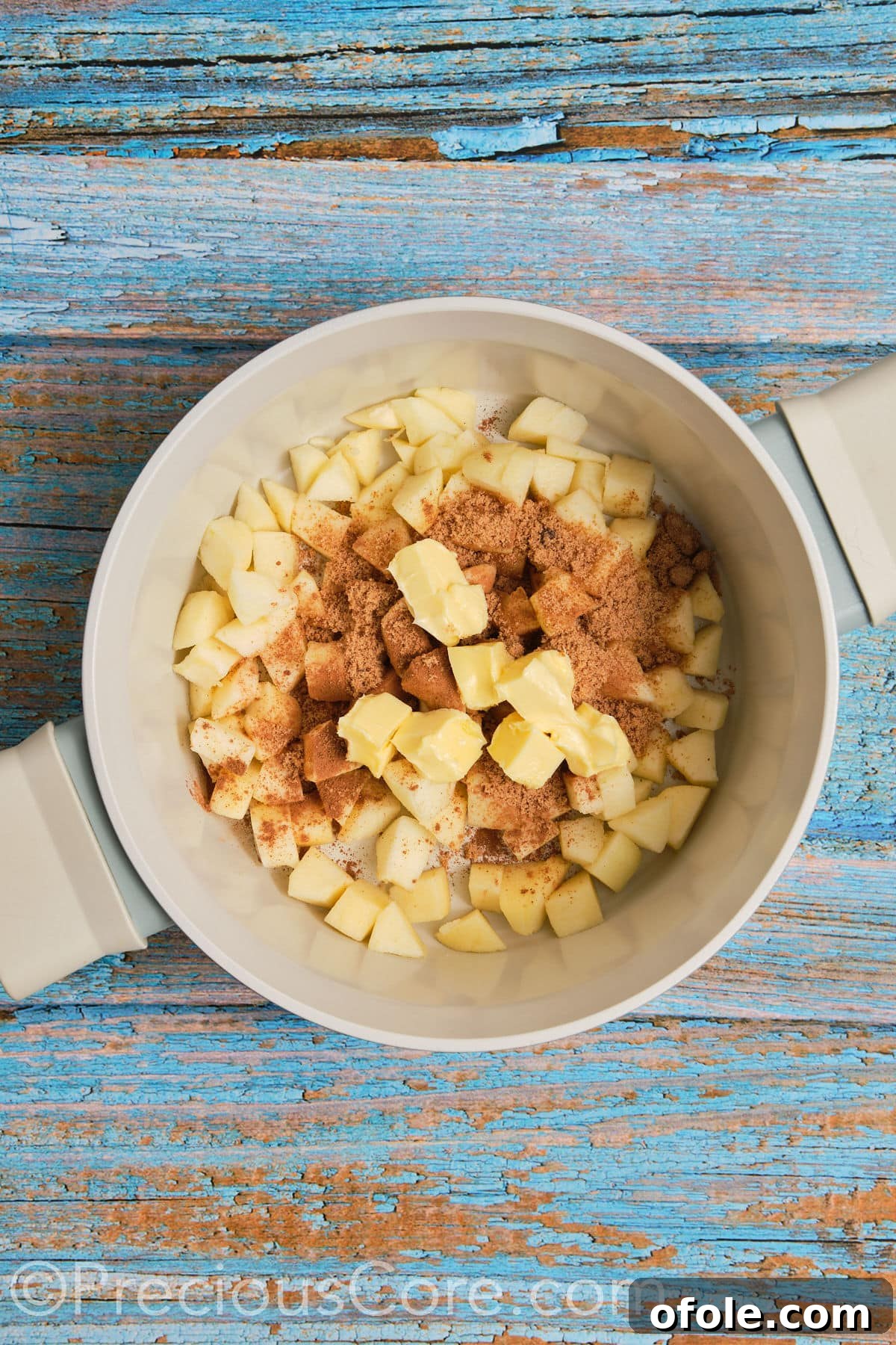 A pot on the stove with butter, brown sugar, cinnamon, and diced apples beginning to cook for the pie filling.