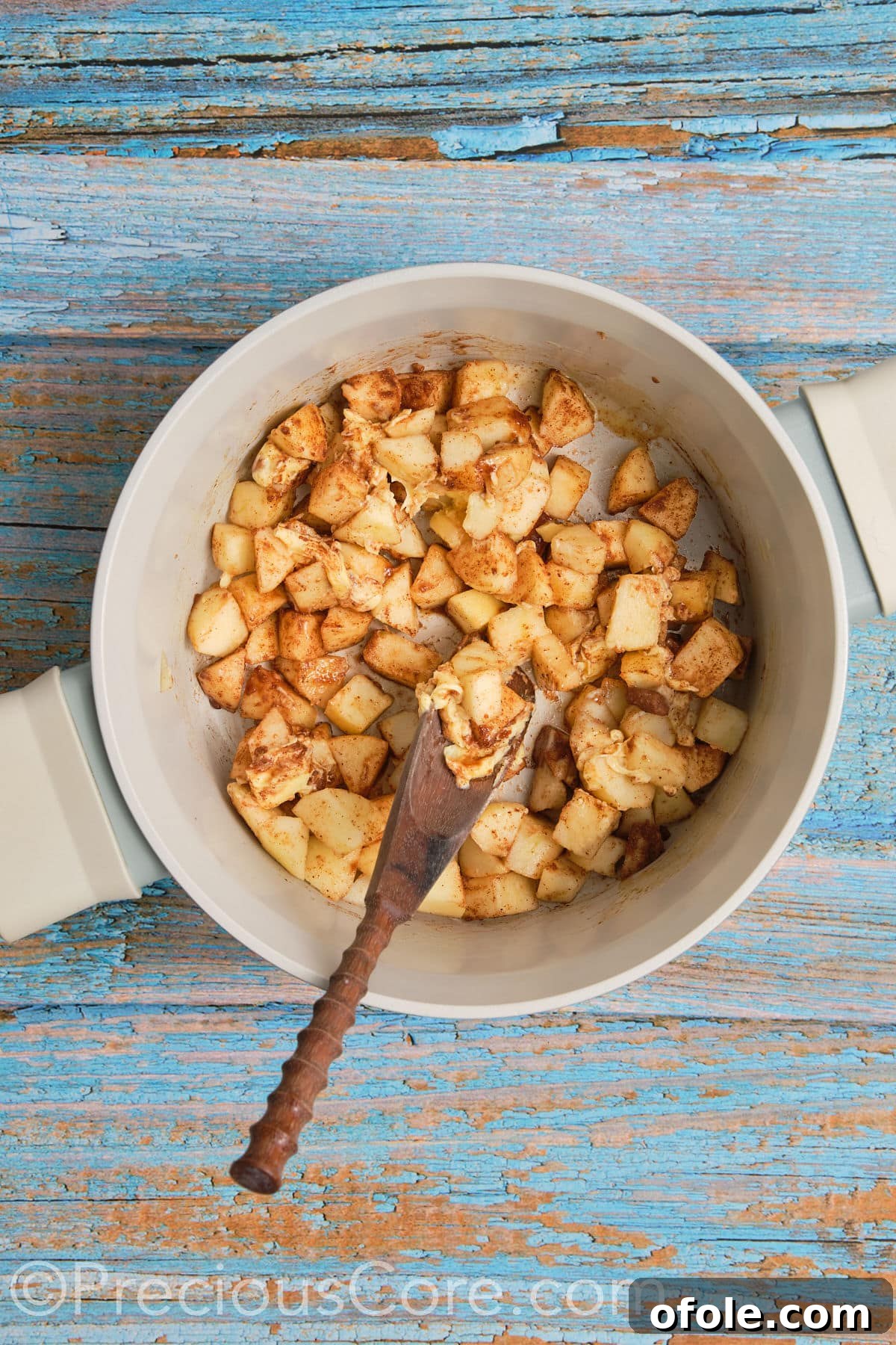 Apple pie filling for cinnamon rolls simmering gently in a pot on the stovetop, as apples soften and flavors meld.